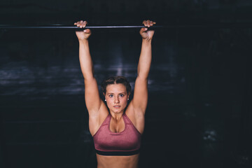 Strong female bodybuilder doing pull-ups for training biceps during workout exercising, portrait of...