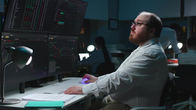 Overweight trader using computer for analyzing data with multi-screens showing real-time stocks