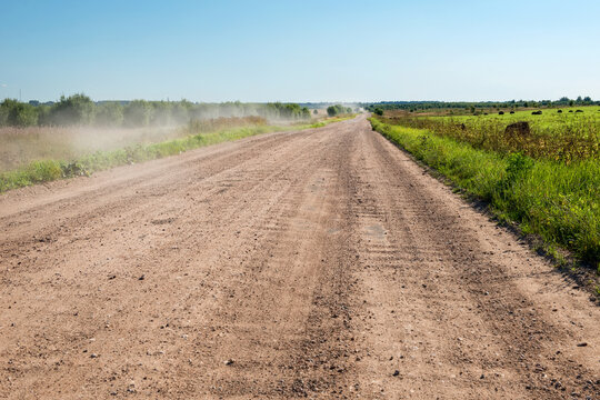 The rural not asphalted road passing through an agricultural field