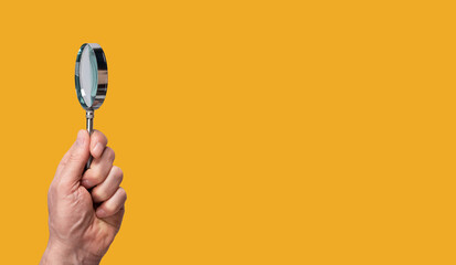 Banner with magnifying glass in man hand on orange background. Copy space. Conducting check...