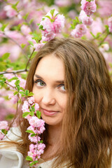 Fototapeta premium Beautiful girl and blooming garden, portrait. Girl in white coat with blooming sakura, apple tree