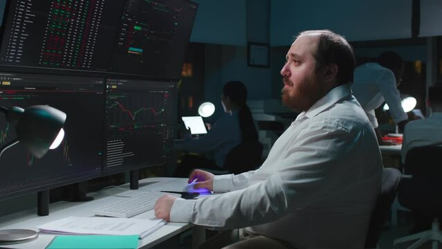 Side view of sad fat broker look at monitors and cry loosing investments money on stock market