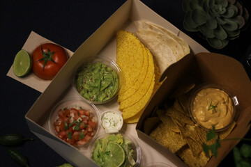 Mexican food box, tex mex, Taco, chili, tortilla, nachos chips, cheddar cheese, guacamole, sour cream, lettuce, tomato