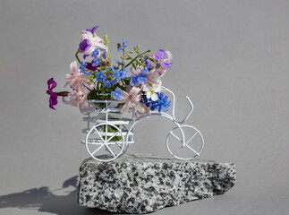 in the basket is a white souvenir bicycle spring bouquet of various small flowers on a gray...