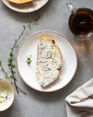 Sandwiches with herbs butter on a gray background. Herb butter in a bowl on concrete background. Healthy homemade herb butter and bread