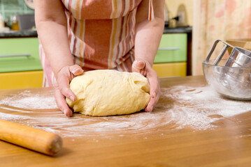 Woman kneading flour in the kitchen at home, hands and dough close-up