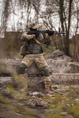 Fototapeta premium Ukrainian soldier of the Armed Forces of Ukraine sits taking aim