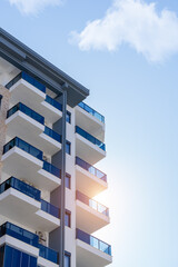 Part of an apartment building with blue sky on a sunny day. - obrazy, fototapety, plakaty