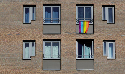Fototapeta na wymiar Rainbow flag on windows of house building on street in colors of gay lgbt lesbians.