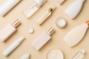 Different cosmetic bottles and container on color background, top view