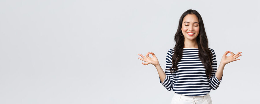 Lifestyle, People Emotions And Casual Concept. Calm Happy Young Woman Feeling Peaceful During Meditation, Close Eyes And Smiling As Hold Hands In Zen Nirvana Gesture, Do Yoga Exercise