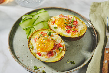 Avocado baked with egg, ham, tomatoes and cheese. Keto lunch recipe. After baking