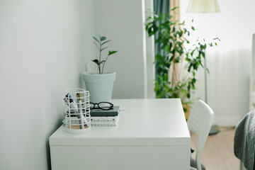 Modern office desk table at home. Workspace with notebook, office supplies, eyeglasses, home plant