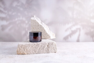  jar of cream on a podium made of stone on a background with abstract shadows, selective focus