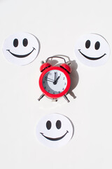 A painted smile and a red alarm clock on a white background . the concept of good mood