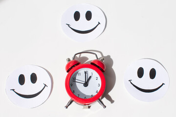 A painted smile and a red alarm clock on a white background . the concept of good mood