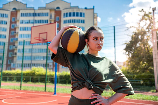 Young pretty sporty caucasian woman hold basketball on basketball court