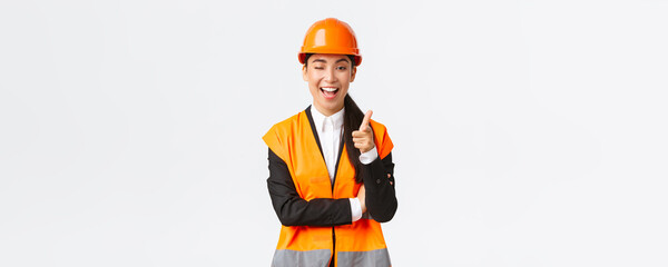 Smiling professional asian female construction manager in safety helmet and reflective jacket...