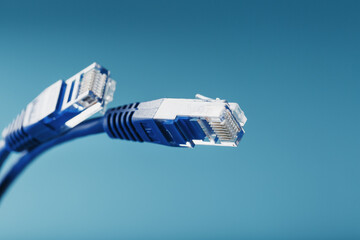 Fototapeta premium Two Ethernet Cable Connectors Patch cord cord close-up isolated on a blue background with free space