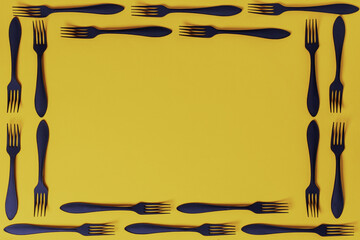 Yellow background with a frame of forks. copy space.