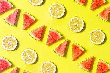Creative pattern with watermelon and lemon slices on sunny yellow background. Colorful summer concept. Minimal fresh fruit idea.