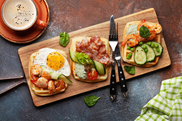 Breakfast waffles with fried eggs, salmon, cucumber and prawns