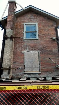 Historic brick summer kitchen building gets a new home. Tiny house is up on stilts and yellow boulders after being moved from a residential district and delivered to its new home in a public park.