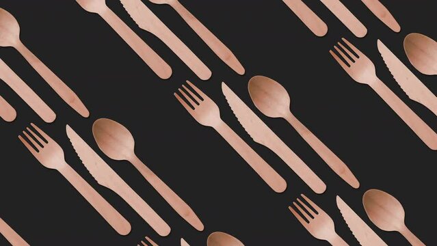 Eco, disposable takeaway wooden cutlery (fork, knife, spoon) on black background. Plastic free, biodegradable, looping animation.