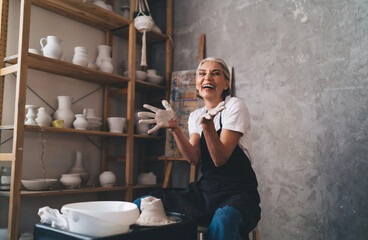 Female sculptor making clay pot on pottery wheel