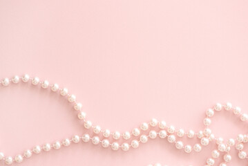 Pearl beads on pastel pink horizintal background with copy space.