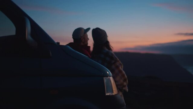 Cinematic lens view, soft blurry focus on young romantic couple, travelers, friends watching colorful stunning sunset, leaning on adventurous camper van, talking about happy future near ocean at Porto