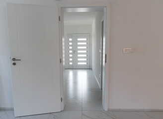 White entrance door with marble tiled floor behind open door