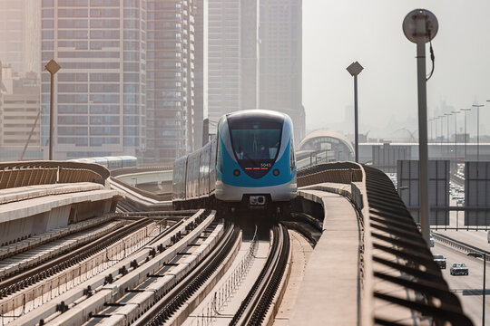 Dubai, United Arab Emirates - November 08, 2021: Dubai metro train on rails at background of skyscrapers. Famous outdoor subway Red Line