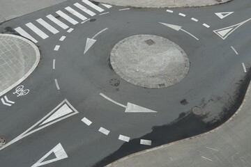 View from top on empty traffic circle or roundabout road with white arrows, crosswalk and other...