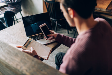 Skilled copywriter creating content plan for web blog using smartphone application while working...