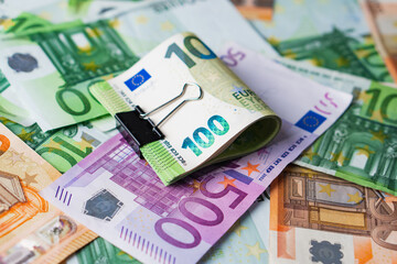 Euro in stationery clip on pile paper banknotes five one hundred and fifty euro. Heap of money