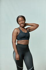 Obraz premium Happy african american woman wears sportive clothes posing. Black girl in sportswear. Body positive and slimming concept