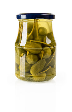 Pickled caper berries in a glass jar isolated on white background. Full glass jar of canned caper fruits. Mediterranean cuisine ingredient. Marinated caperberry as condiment and garnish.