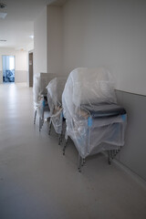 many chairs are stacked and covered with foil in the hallway