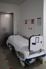 patient transport bed stands in front of an elevator in a hospital