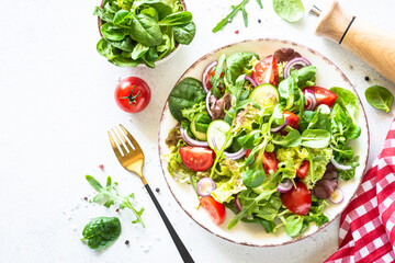 Salad in white plate. Fresh green leaves and vegetables salad. Healthy vegan food, diet food. Top view, copy space.