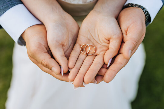 The bride and groom hold gold rings in their hands, close-up on the palms. Wedding portrait, photography.