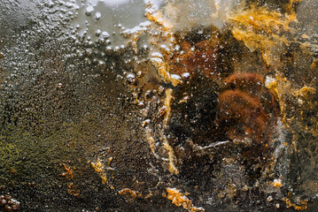 Texture, background, top view of a black tray smeared in fat, oil, pieces of old meat, after cooking. Food photography, abstraction, top view.