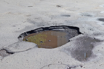 The asphalt pavement on the road was destroyed. Poor condition of roads requiring repair. View from above. Construction and repair of roads. A hole in the asphalt - Powered by Adobe