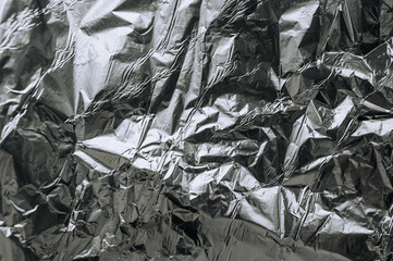 Background, texture of silver shiny foil, colored crumpled old paper for packing goods. Close-up photo, top view, copy space, abstraction.