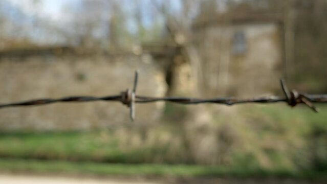 Person walking to the barb wired fence, point of view, handheld shot. Approaching the barbed wire until it comes into focus