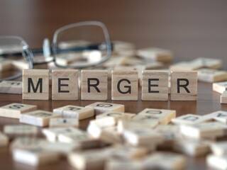 merger word or concept represented by wooden letter tiles on a wooden table with glasses and a book