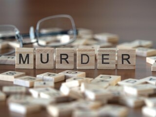 murder word or concept represented by wooden letter tiles on a wooden table with glasses and a book