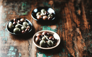 Various olives on rustic wooden background. Copy space.