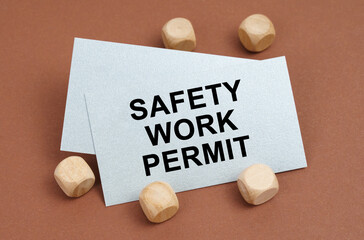 On a brown surface, wooden cubes and a business card with the inscription - Safety Work Permit